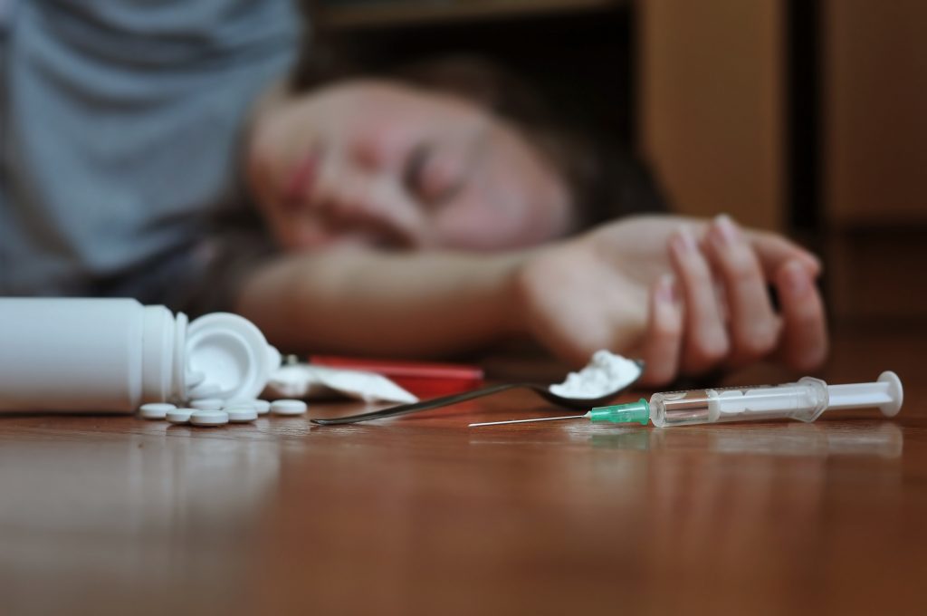 drug addict on floor with drugs